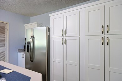 Kitchen with white cabinets, stainless steel fridge with ice dispenser, a textured ceiling, and light countertops