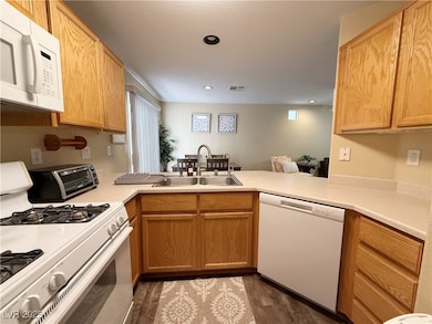 Kitchen with white appliances, a peninsula, wood f