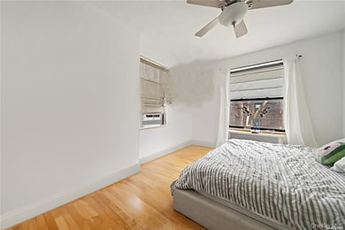 Bedroom with cooling unit, hardwood / wood-style floors, and ceiling fan