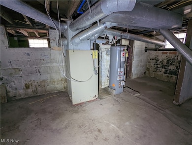 Basement featuring gas water heater, heating unit, and healthy amount of natural light