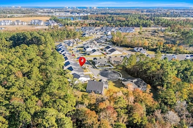 Aerial view of property's location featuring a tree filled landscape and nearby suburban area