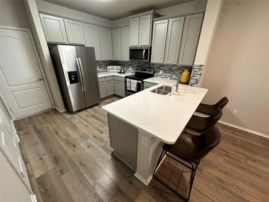 Kitchen with sink, backsplash, gray cabinets, appliances with stainless steel finishes, and a breakfast bar area