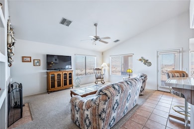 Living area featuring lofted ceiling, a ceiling fa