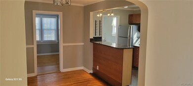 Kitchen with crown molding, stainless steel fridge, an inviting chandelier, light wood-type flooring, and decorative light fixtures. View from Family room into arched opening, dining/breakfast nook area.  Door straight ahead is great formal dining or homeschool/office area.