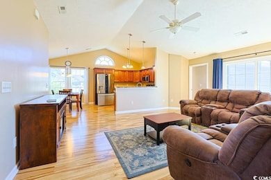 Living room featuring light wood finished floors, a chandelier, high vaulted ceiling, and ceiling fan