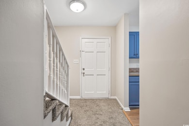 Entryway featuring stairs, baseboards, and carpet 