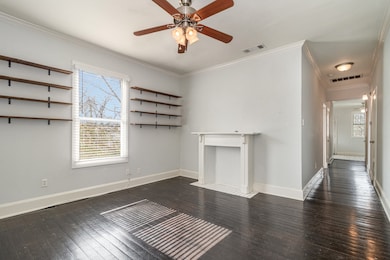 Unfurnished living room with dark wood-type flooring, ornamental molding, and ceiling fan
