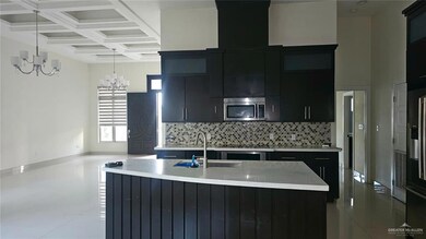 Kitchen with dark cabinetry, decorative light fixtures, a kitchen island with sink, appliances with stainless steel finishes, and decorative backsplash