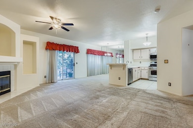 Unfurnished living room featuring a fireplace, light carpet, a ceiling fan, light tile patterned flooring, and a textured ceiling