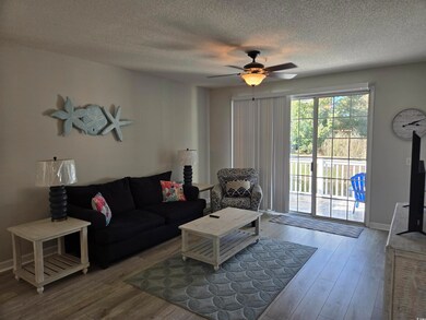 Living area with a textured ceiling, wood finished floors, and a ceiling fan