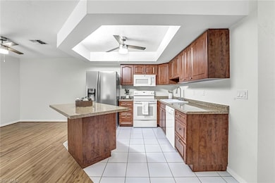 Kitchen with white appliances, ceiling fan, a sink