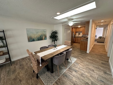 Dining room with dark wood-type flooring, a textured ceiling, and ceiling fan
