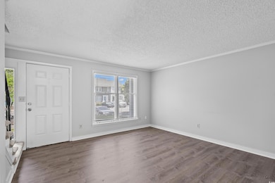 Foyer entrance with a textured ceiling, dark wood finished floors, and crown molding