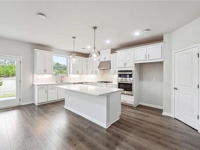 Kitchen featuring under cabinet range hood, plenty of natural light, stainless steel double oven, white cabinets, and recessed lighting