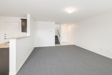 Empty room featuring light carpet and stairway