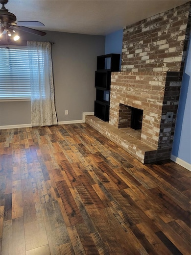 Unfurnished living room featuring dark wood finished floors, a fireplace, and ceiling fan