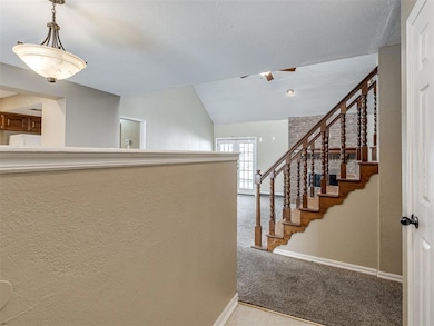 Hall featuring light colored carpet, lofted ceiling, a textured wall, french doors, and a textured ceiling