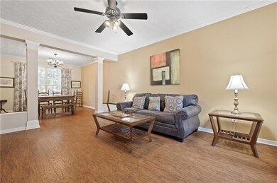 Living area with ornate columns, baseboards, wood 