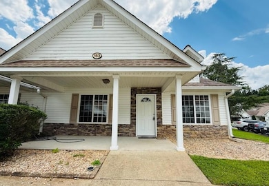 View of front of house with roof with shingles, a porch, and stone siding