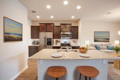 Kitchen with decorative backsplash, appliances with stainless steel finishes, dark brown cabinets, a breakfast bar, and an island with sink