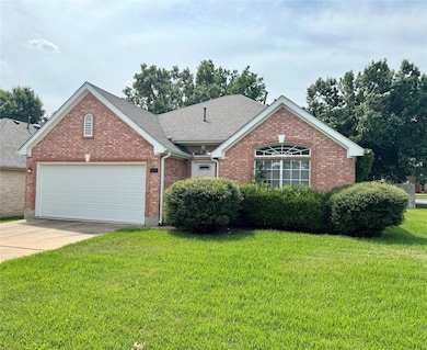 Ranch-style home with a front yard, brick siding, concrete driveway, and a garage
