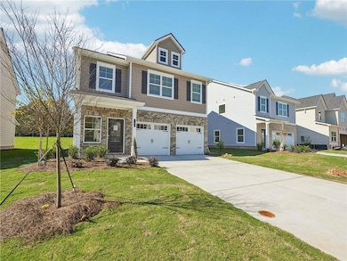View of front of property with driveway, a garage, stone siding, and a front yard