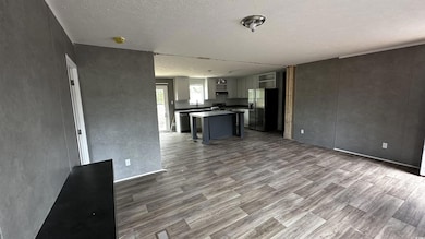 Unfurnished living room featuring a textured ceili