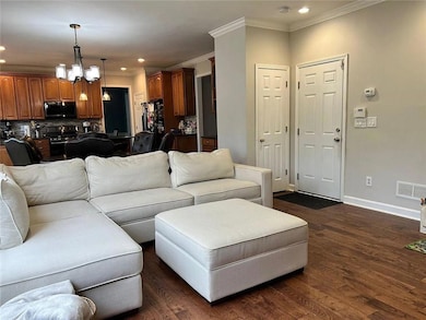 Living room with ornamental molding, recessed lighting, baseboards, dark wood-style flooring, and a chandelier