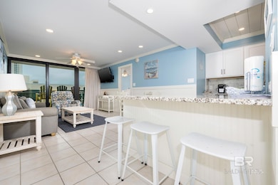 Kitchen with wainscoting, a kitchen breakfast bar, recessed lighting, light stone counters, and backsplash