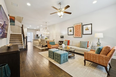 Living room featuring stairway, a ceiling fan, recessed lighting, dark wood finished floors, and a chandelier