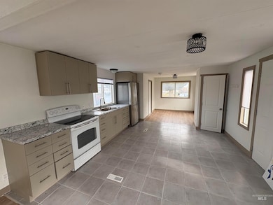 Kitchen with white range with electric cooktop, healthy amount of natural light, freestanding refrigerator, and gray cabinets