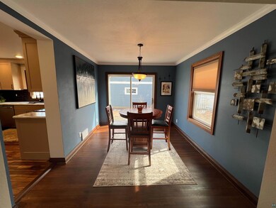 Dining space featuring dark wood-type flooring, visible vents, ornamental molding, and baseboards