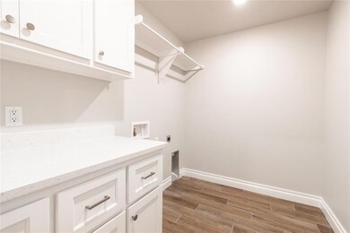 Kitchen view of backsplash, white cabinets, stainless steel gas cooktop, light stone countertops, and wood finished floors