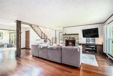 Living room with stairs, hardwood / wood-style floors, healthy amount of natural light, and a textured ceiling