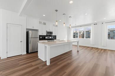 Kitchen featuring stainless steel appliances, decorative backsplash, glass insert cabinets, white cabinetry, and decorative light fixtures