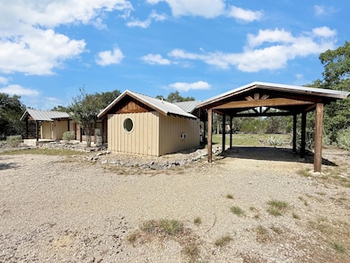View of outdoor structure featuring a carport and gravel driveway