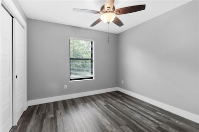 Unfurnished bedroom with a ceiling fan, dark wood-