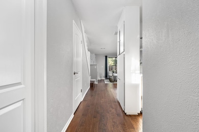 Hall with a textured wall, wood-type flooring, an