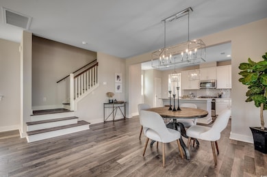 Dining area featuring a chandelier, dark wood finished floors, and stairs
