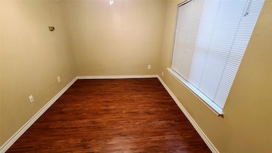 Spare room featuring baseboards and dark wood-sty