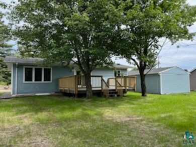 Rear view of house with a wooden deck and a lawn