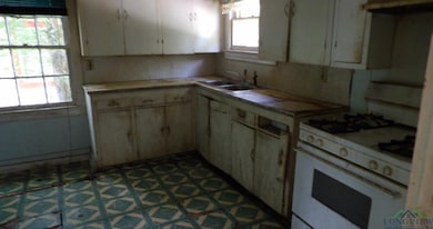 Kitchen with white range with gas stovetop, tile patterned floors, and tile countertops