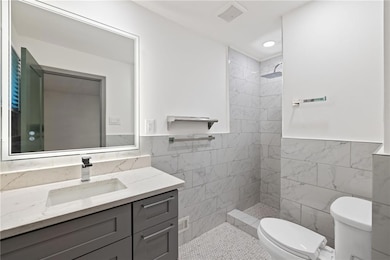 Bathroom featuring tile walls, vanity, toilet, a t
