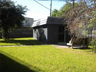 Rear view of property with brick siding, an outbuilding, mansard roof, and a patio area