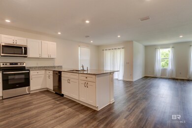 Kitchen with dark hardwood / wood-style flooring, white cabinets, sink, appliances with stainless steel finishes, and kitchen peninsula