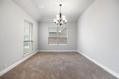 Empty room with visible vents, a chandelier, carpet, baseboards, and vaulted ceiling