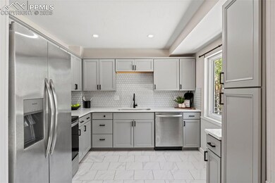 Kitchen with stainless steel appliances, a sink, gray cabinetry, light countertops, and recessed lighting