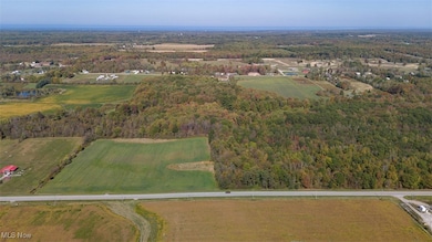 Aerial view of property and surrounding area featuring a heavily wooded area and rural landscape