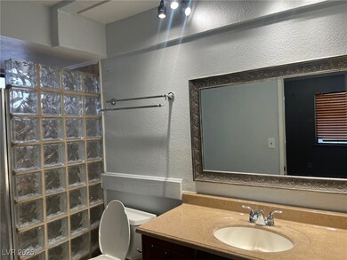 Bathroom with toilet, a textured wall, a walk in s