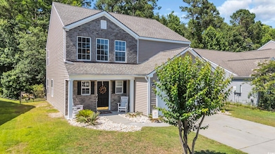 Traditional-style house with covered porch, driveway, a shingled roof, and stone siding